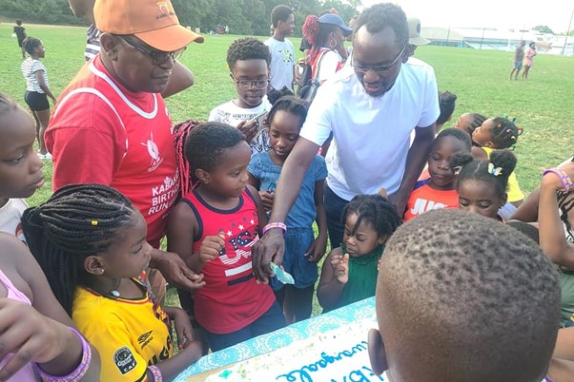 Young ones with Owek Kajubi while cutting the cake Image